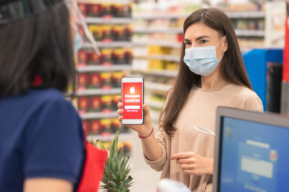 Woman with face mask using digital grocery coupon